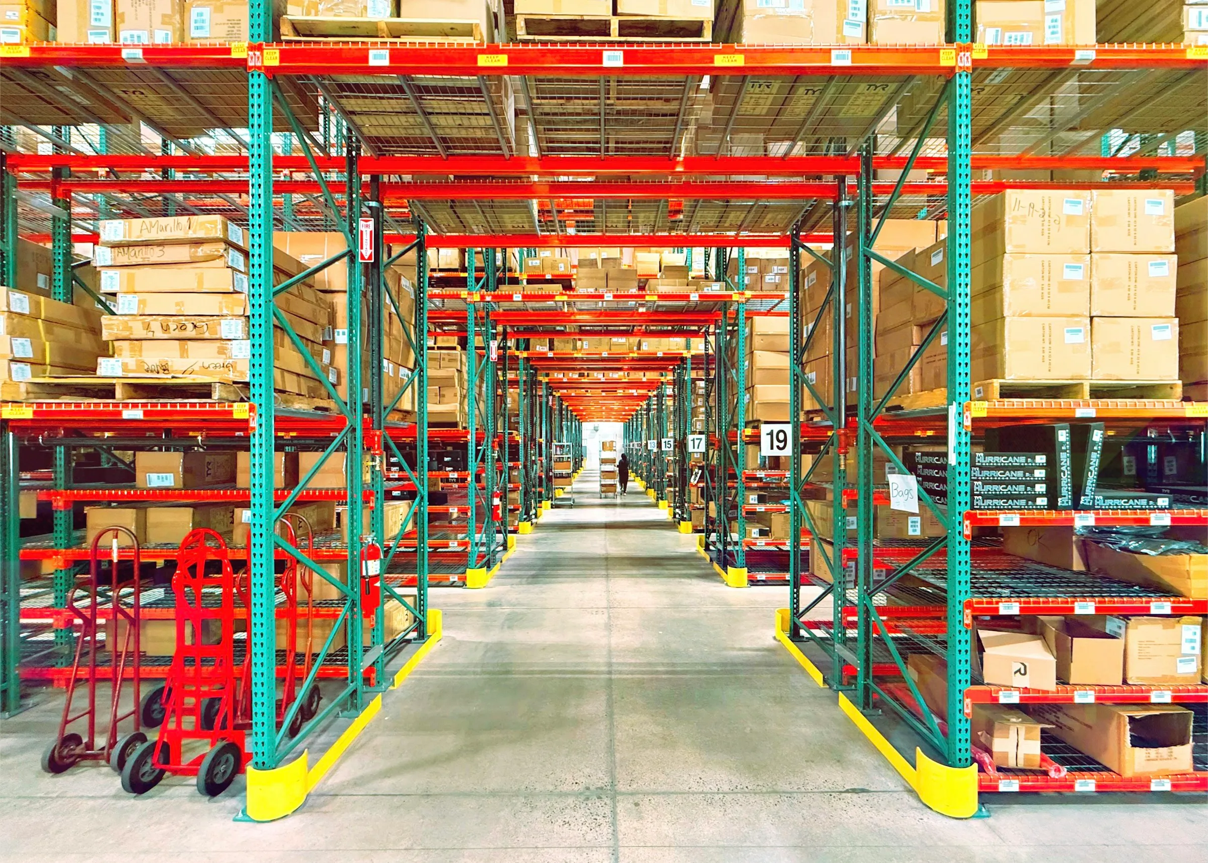 A warehouse aisle lined with pallet racking stocked with boxed goods